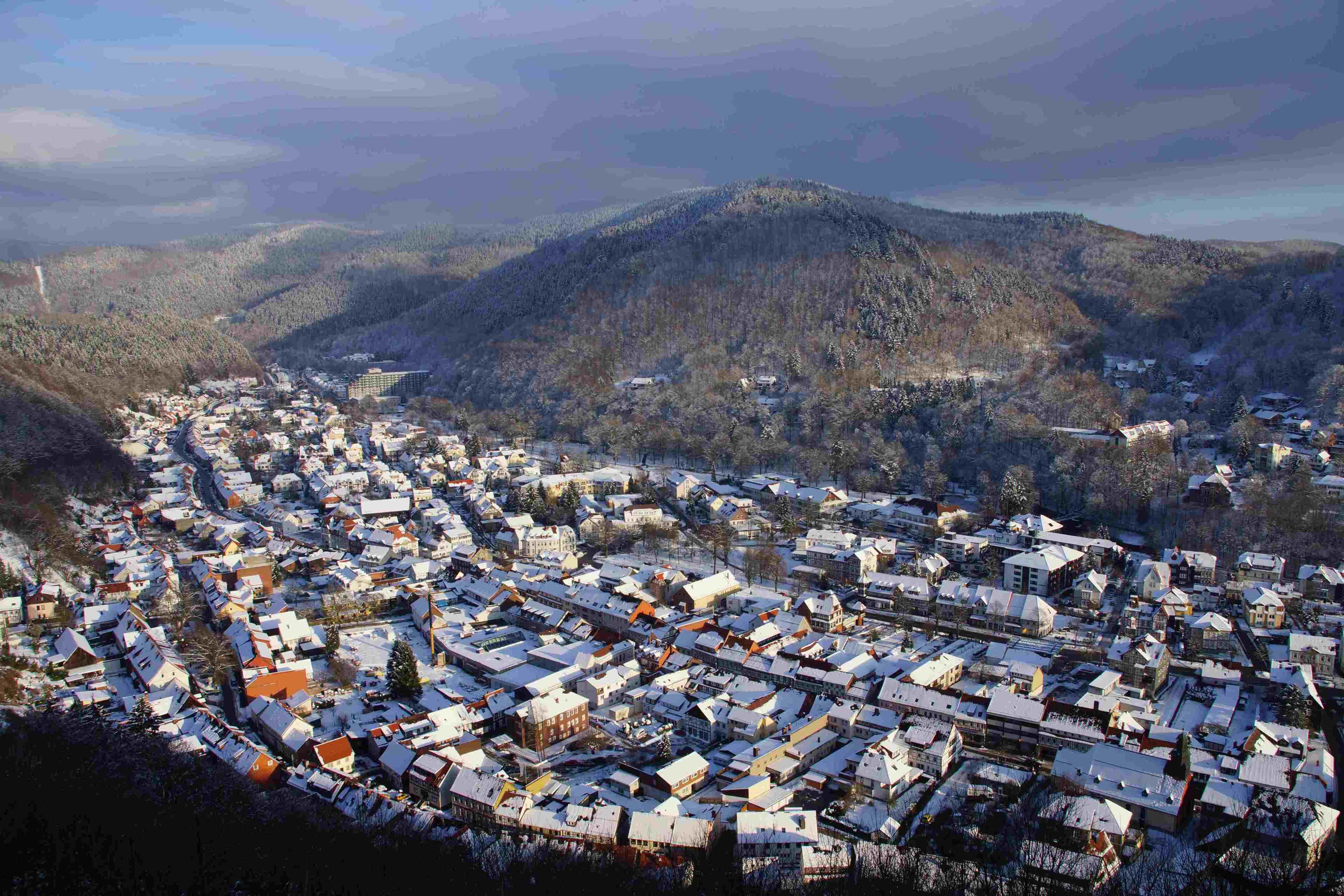 Un pueblo con edificios cubiertos de nieve y montañas al fondo.