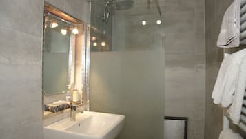 A modern bathroom with a glass-enclosed shower, a white sink, and a large mirror.