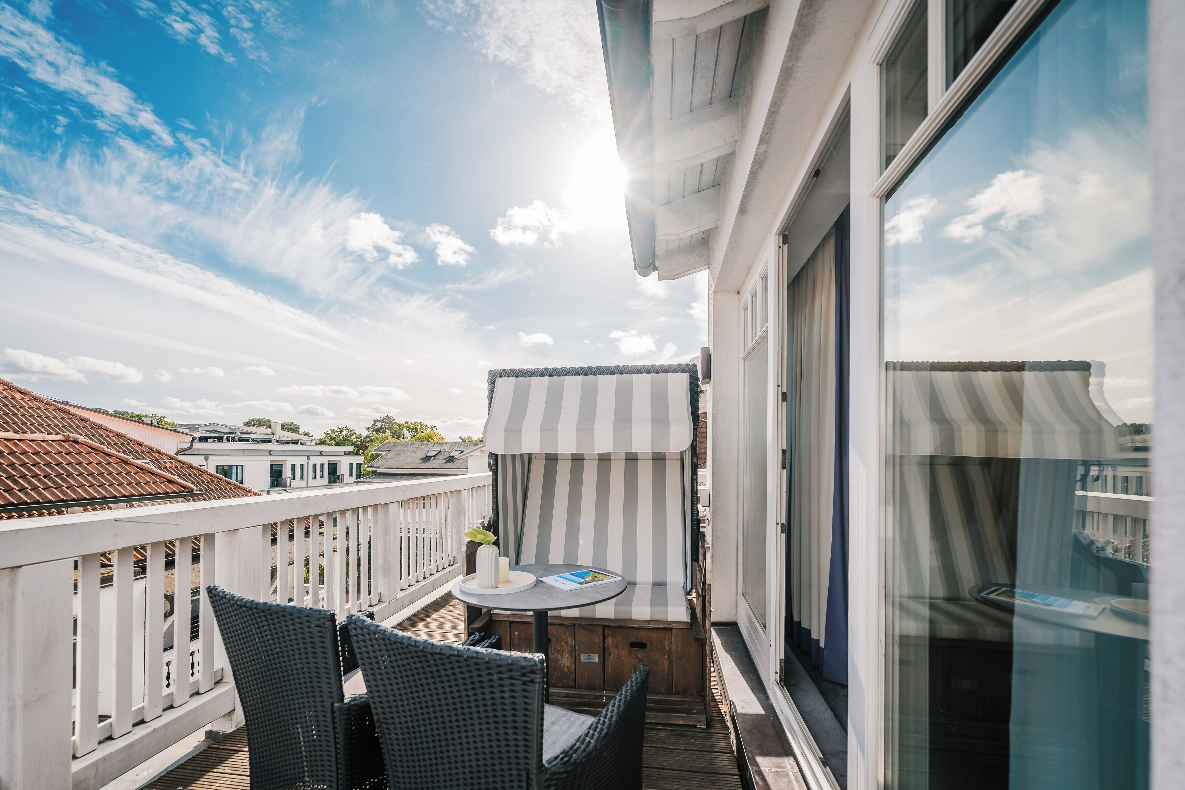 A balcony with wicker chairs, a small round table, and a striped awning.