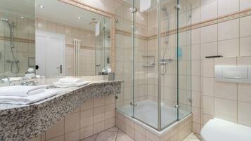 A modern bathroom with a glass-enclosed shower, a large mirror, and a granite countertop.