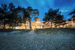 Una propiedad frente a la playa con un camino que lleva a un edificio de varios pisos y balcones.