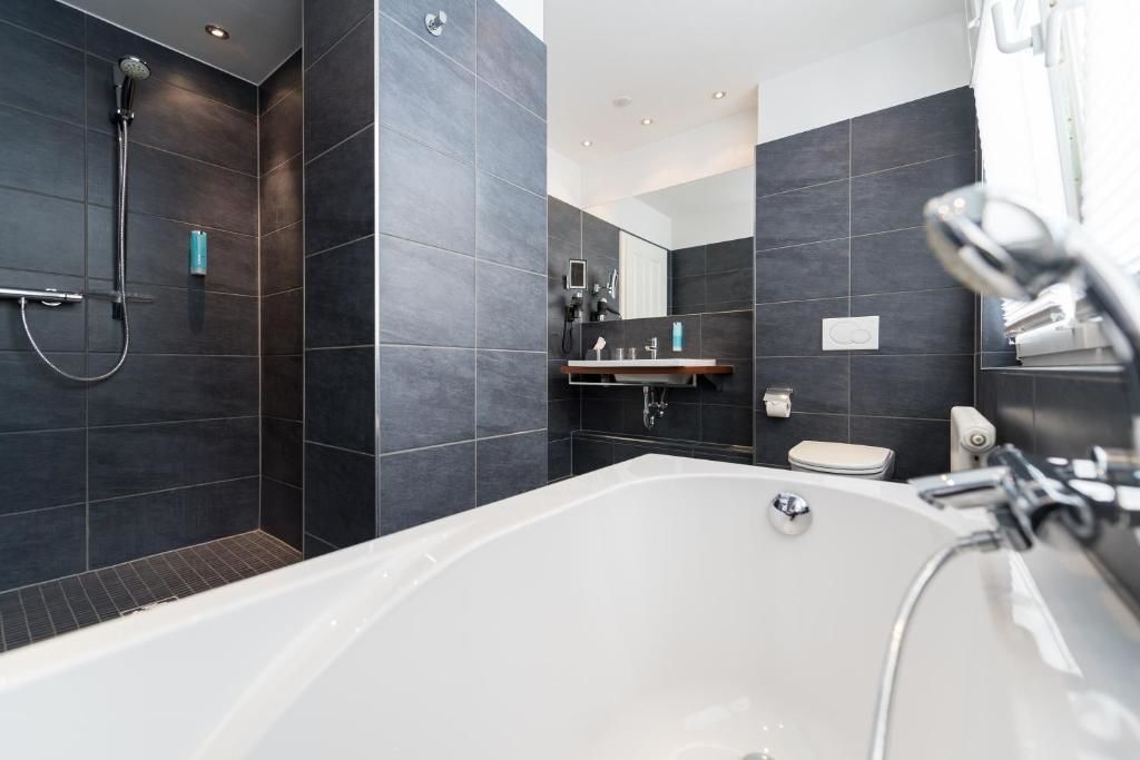 Un baño moderno con una bañera grande, zona de ducha y tocador con espejo.
