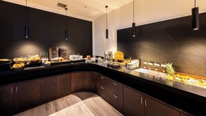 Une cuisine moderne avec des meubles de couleur sombre, un comptoir incurvé et des luminaires suspendus.
