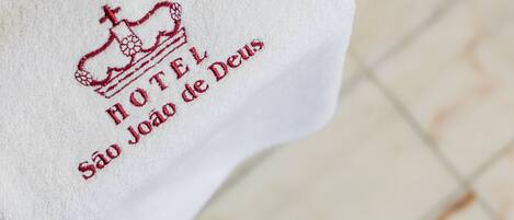 Une serviette blanche ornée d’un texte brodé et d’un motif représentant une couronne.