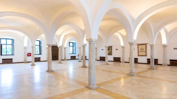 Un saló ampli amb alçades elevades, arcs blancs i paviment de marbre.