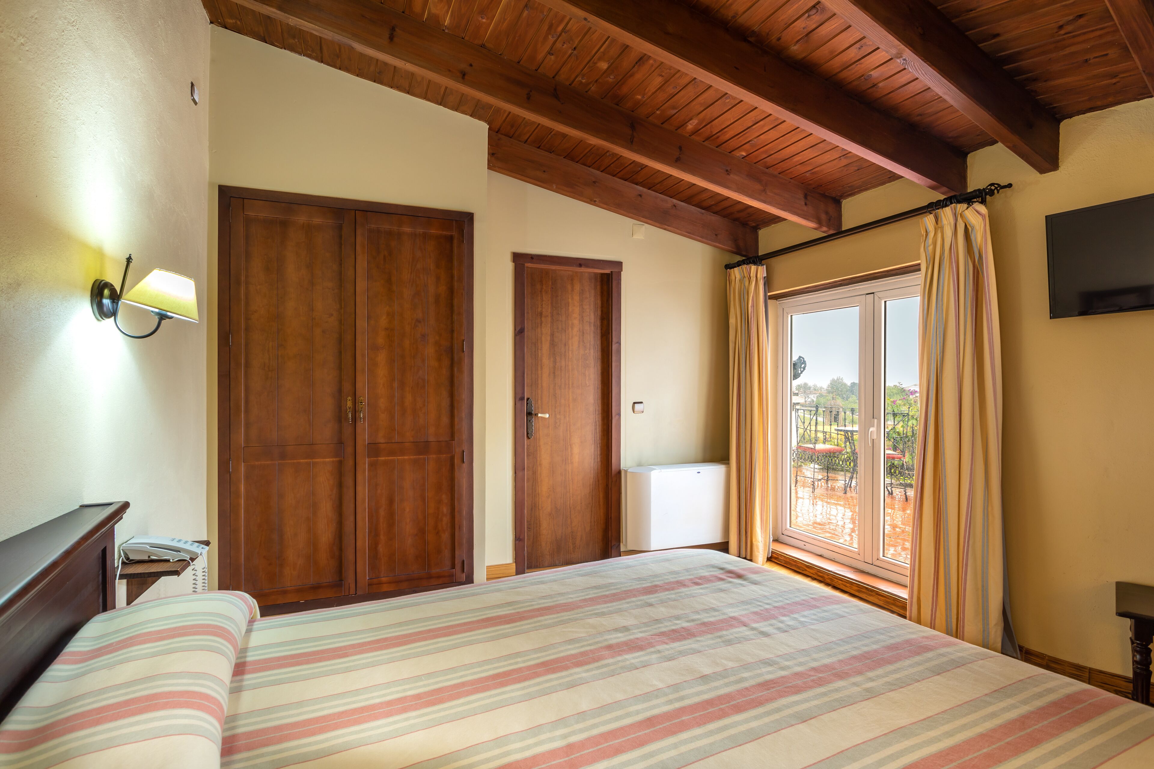 Un dormitorio con cama, armario de madera y puerta corredera de vidrio a un patio.