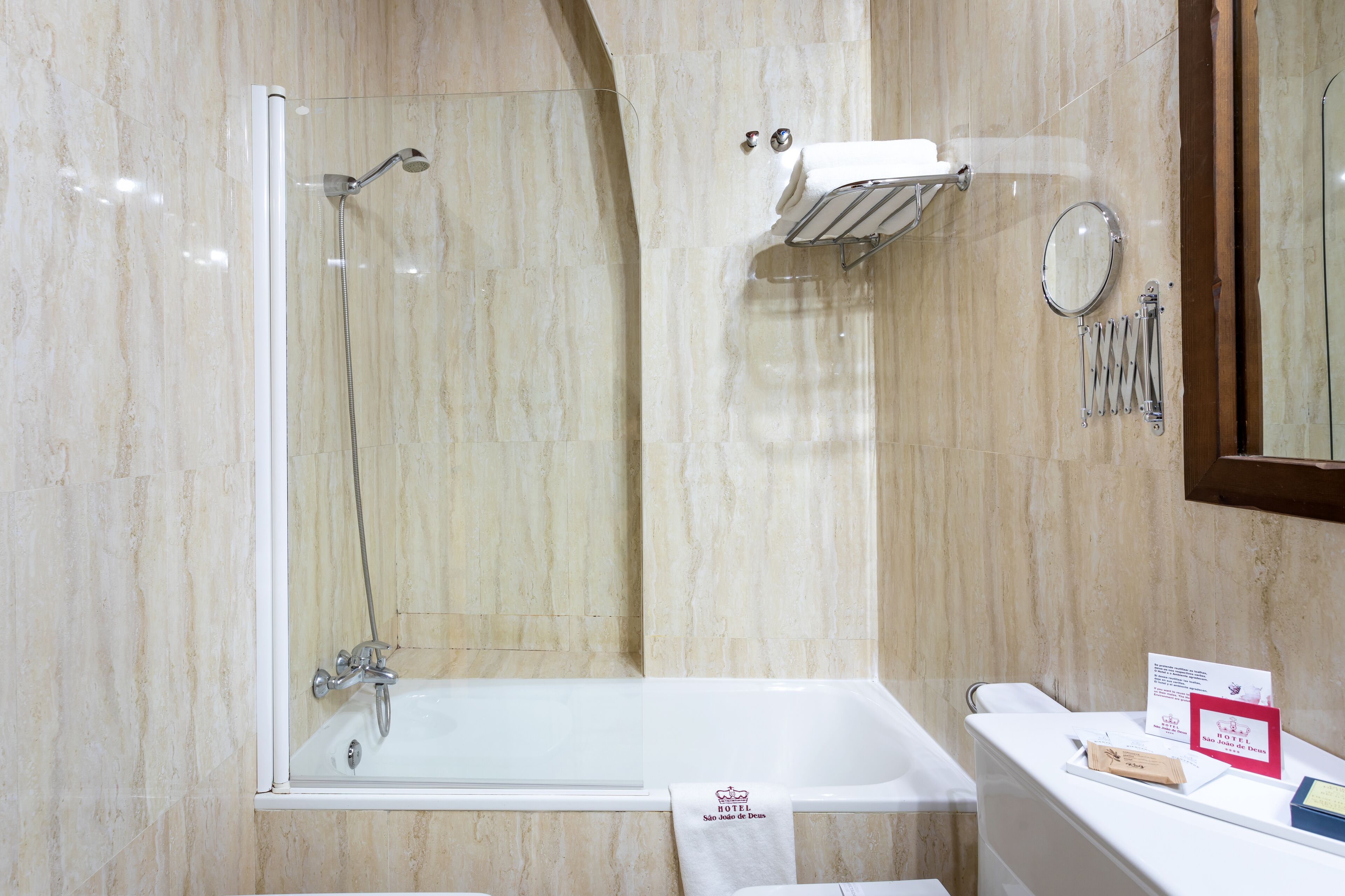 Un baño con ducha envuelta en vidrio, una bañera y un tocador con espejo y perchero para toallas.