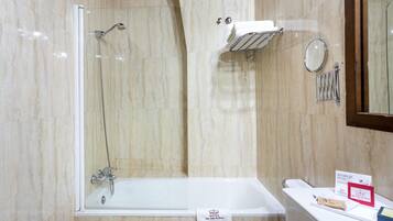 Un baño con ducha envuelta en vidrio, una bañera y un tocador con espejo y perchero para toallas.