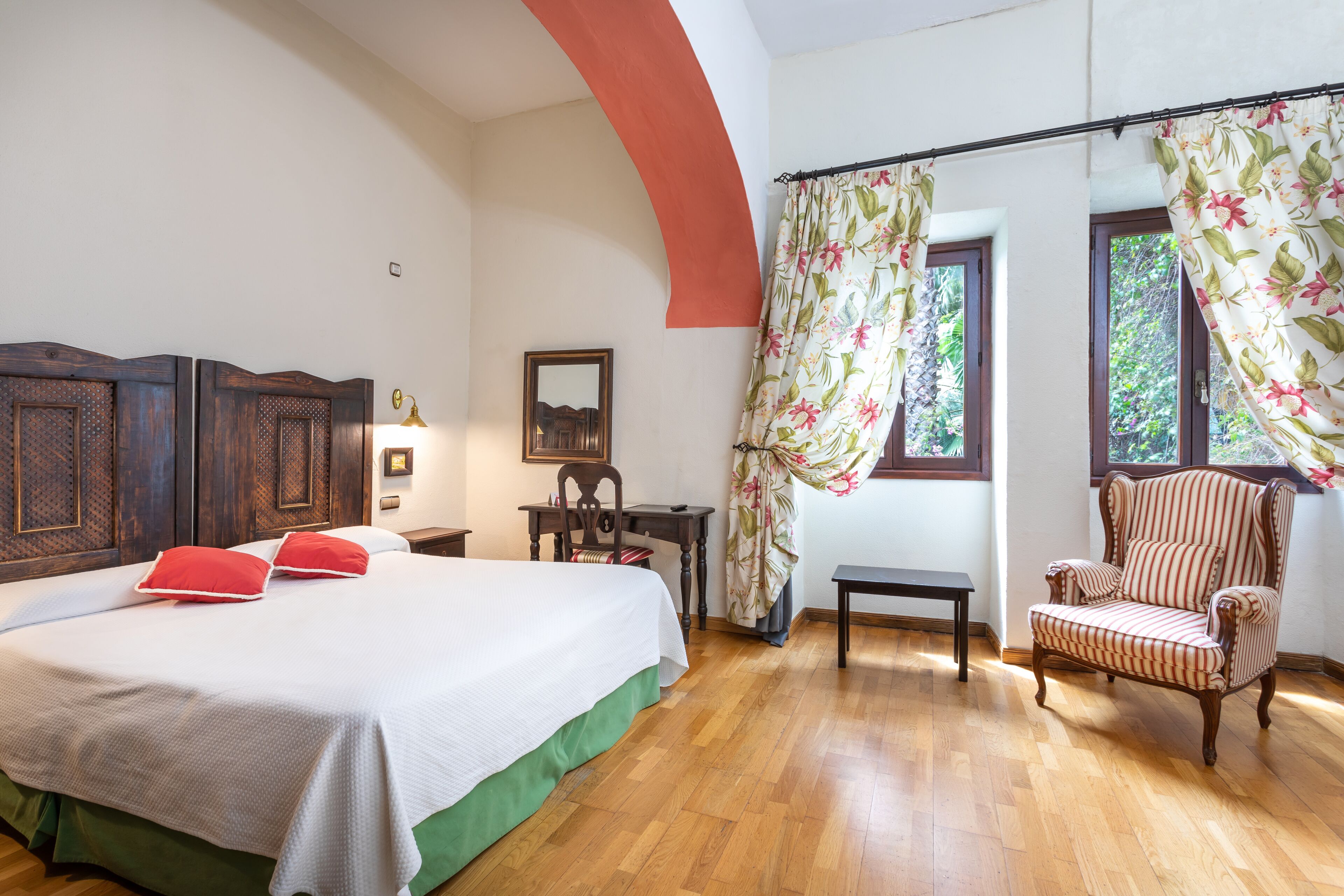 Un dormitorio con una cama grande, una silla, una mesa y cortinas.