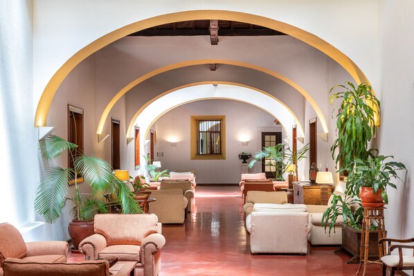 Un hall d’entrée spacieux avec des plafonds en arc de cercle, des sièges confortables et des plantes en pot.