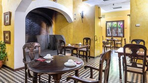 Un restaurant amb un sòl de pissos, taules i cadires de fusta i una llar de pedra.