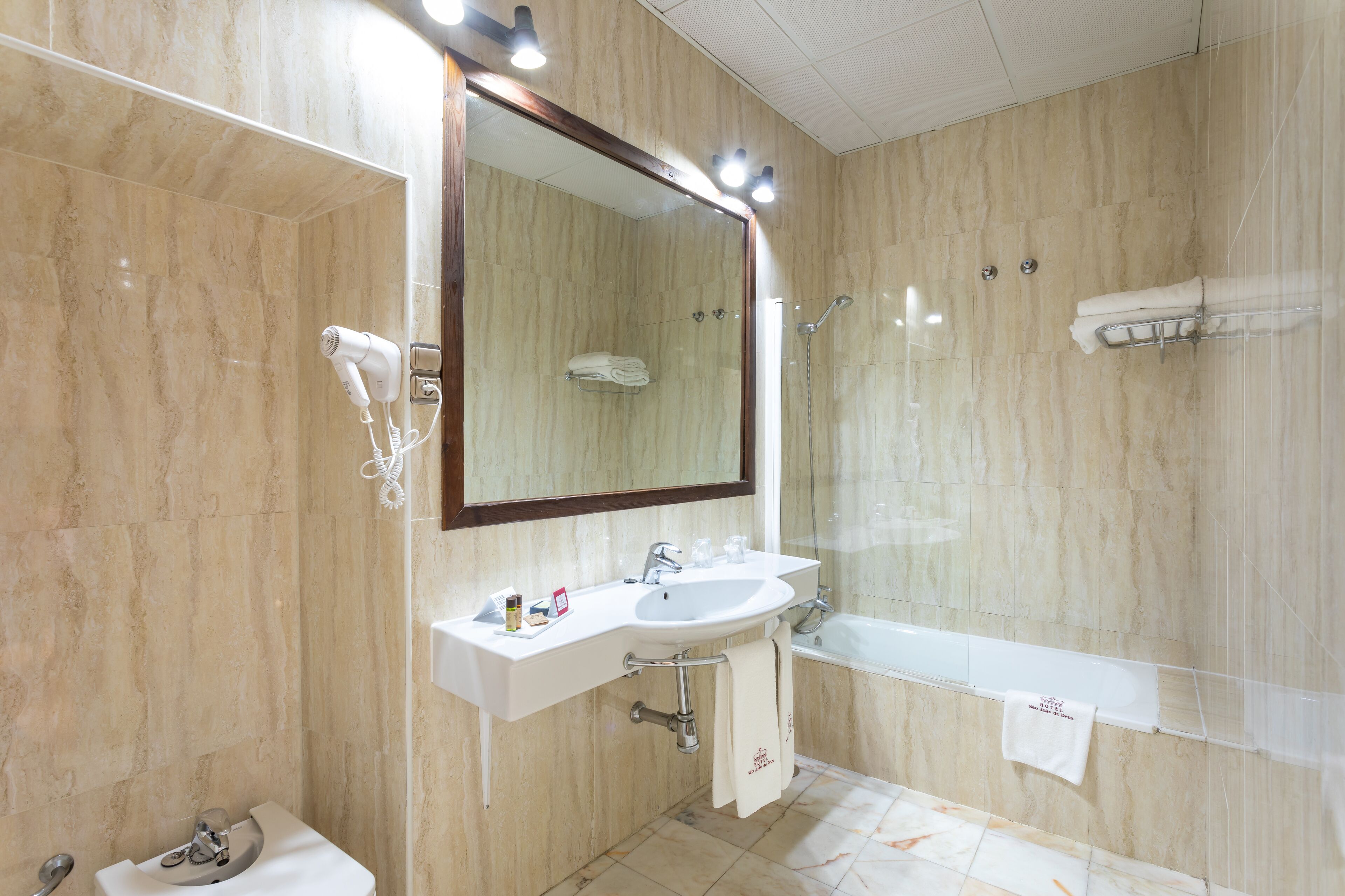 A modern bathroom with a large mirror, a sink, a toilet, and a bathtub.