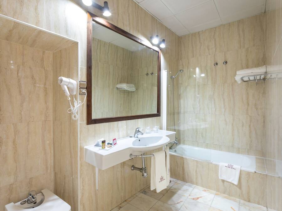 Et moderne badeværelse med et stort spejl, en vask, et toilet og et badekar.