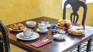 Una mesa de desayuno dispuesta con cruasanes, café, fruta y pastelería.