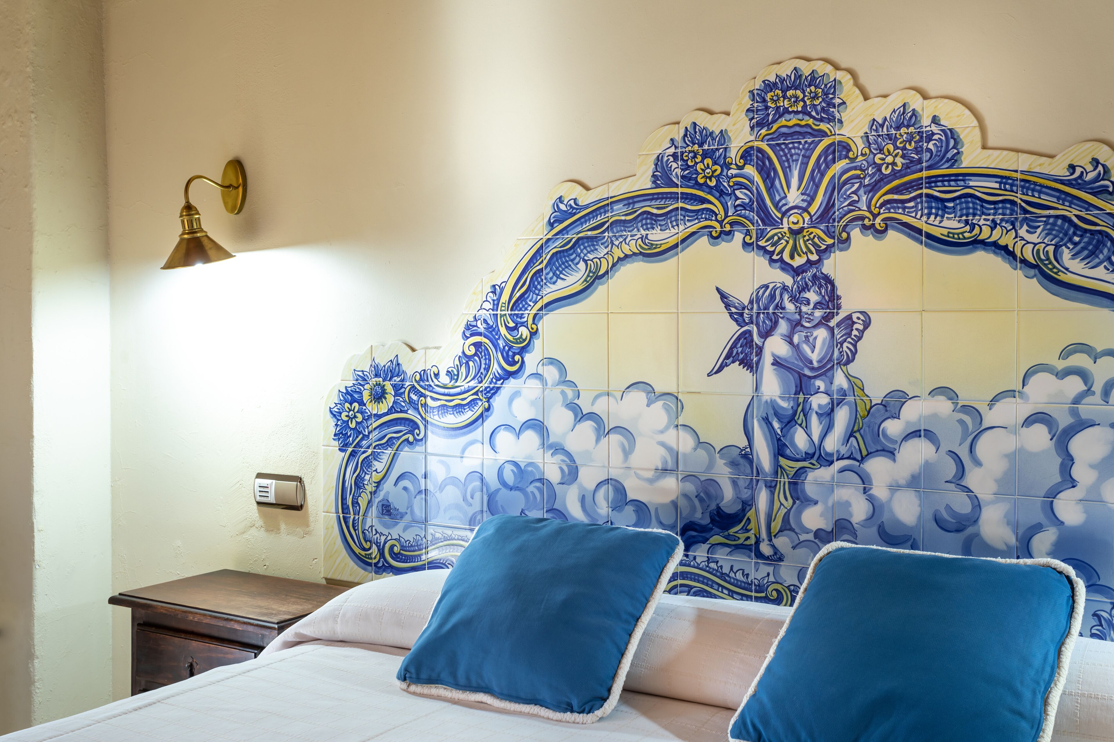 A bedroom with a decorative tiled headboard, a bedside table, and two pillows.