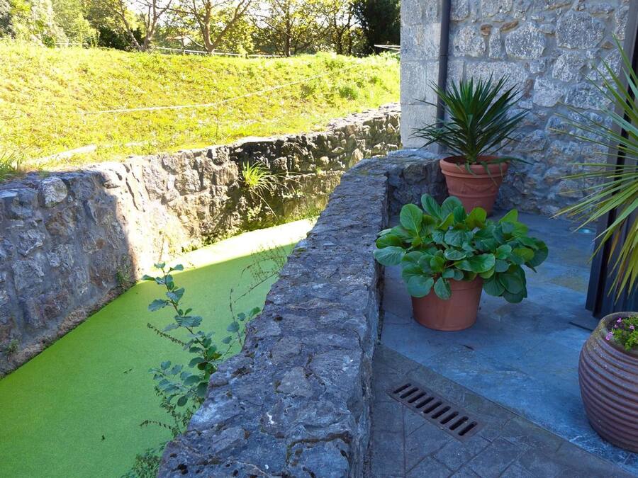 A stone wall with a small water feature and potted plants.