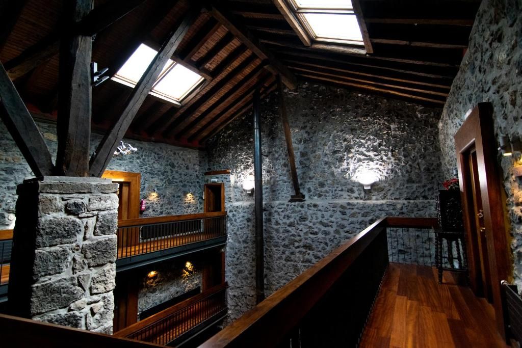 A rustic interior with stone walls, wooden beams, and a fireplace.