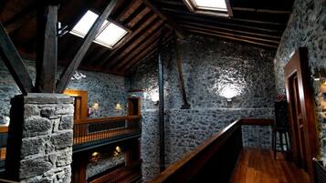 A rustic interior with stone walls, wooden beams, and a fireplace.