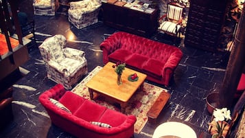 Una zona de estar acogedora con un sofá rojo, sillones estampados y una mesa de centro de madera.