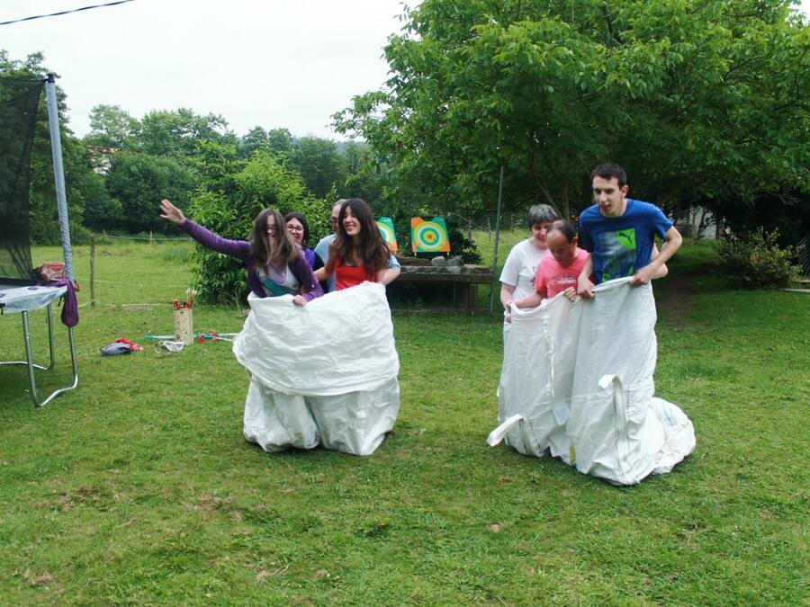 A group of people in a grassy outdoor area with a trampoline and a target in the background.