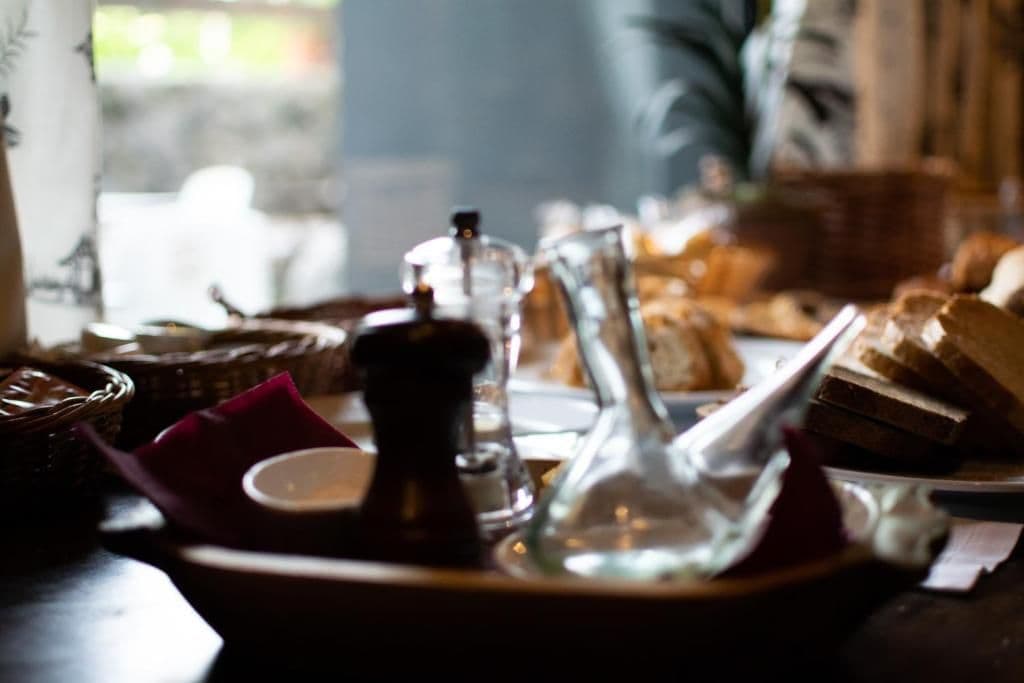 A dining table with bread, a coffee pot, and a pitcher.