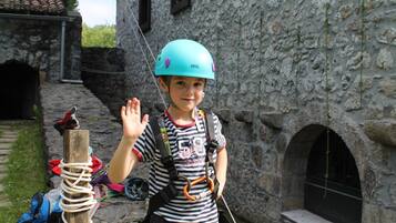 A child in a striped shirt and helmet standing in front of a stone building with an arched doorway.