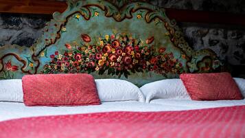 A bed with a floral headboard and red pillows.