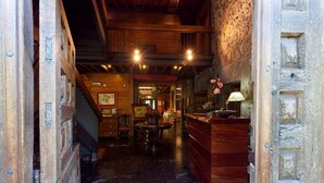 A wooden interior with a reception desk, a staircase, and a dining area.