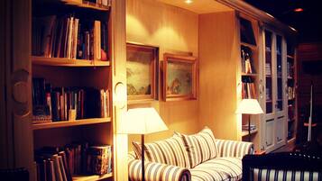 A cozy room with a striped sofa, two lamps, and bookshelves filled with books.