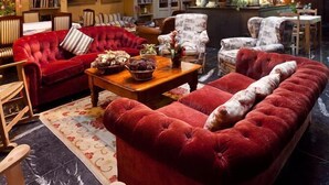 A spacious lobby with a high ceiling, a stone fireplace, and a comfortable seating area with red sofas and armchairs.