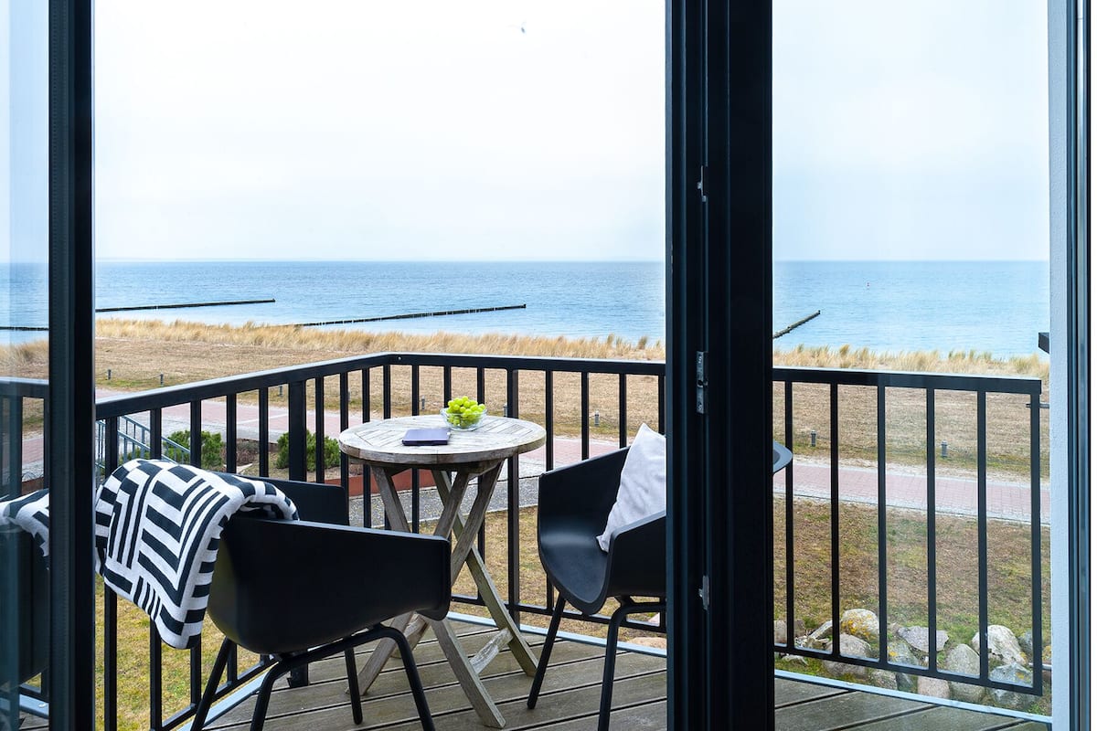 Un balcon avec vue sur la mer, comprenant une table avec un saladier de fruits et une chaise.