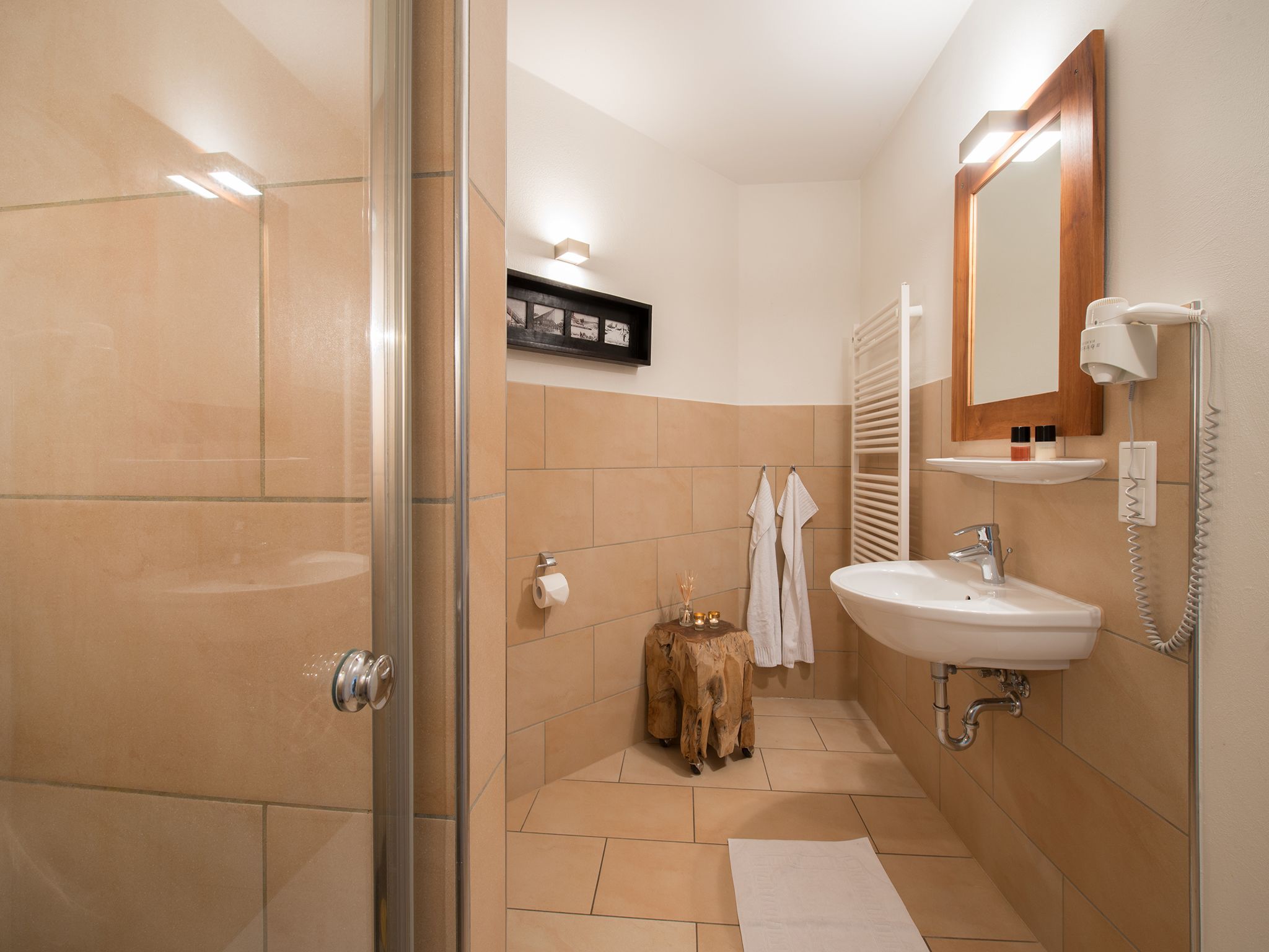 Un baño con mampara de vidrio, lavamanos, espejo y toallero.