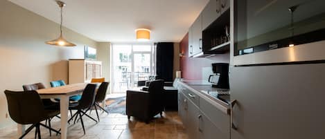 A modern kitchen with a dining area, featuring a large table, chairs, and a refrigerator.