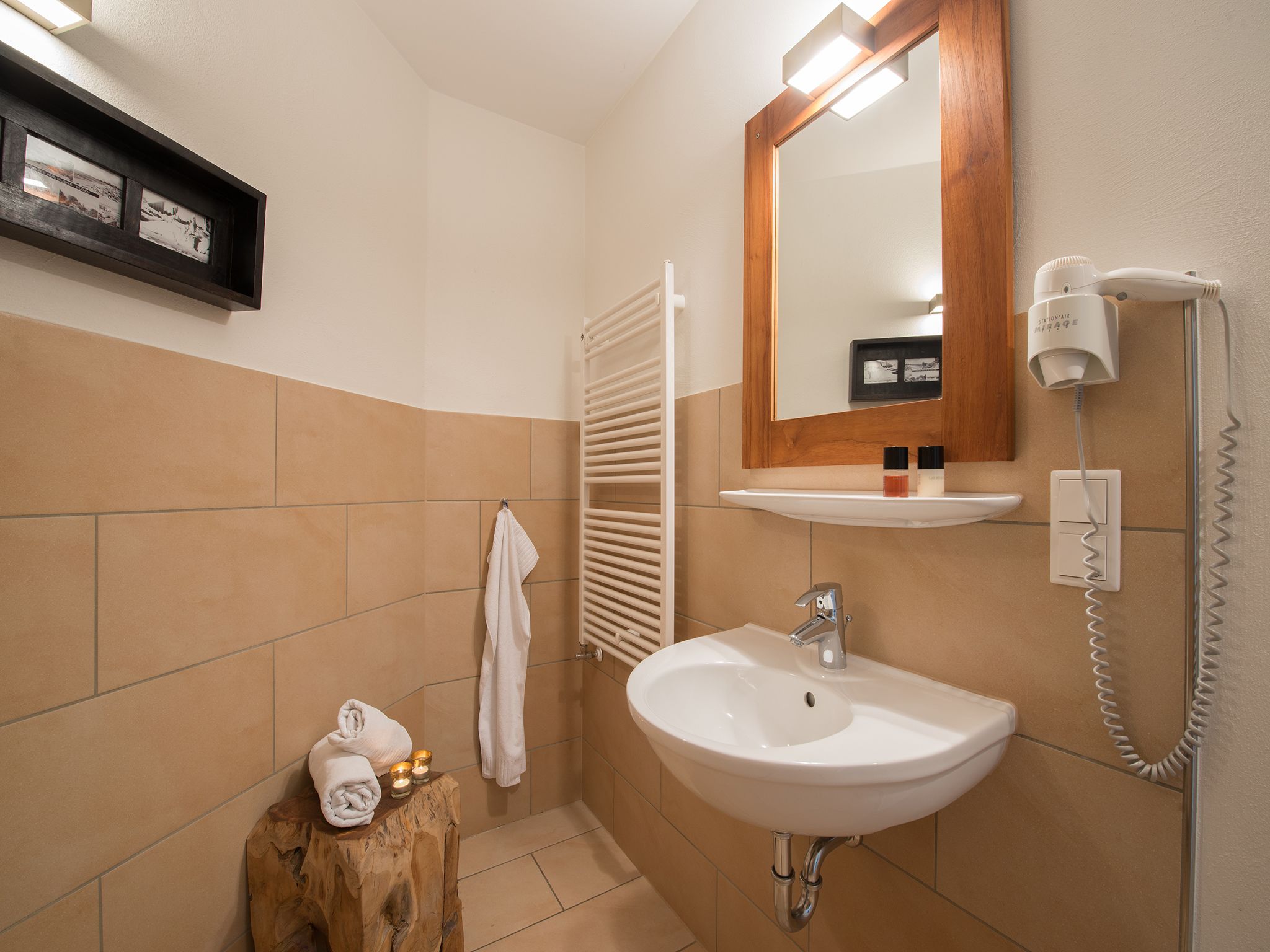 A bathroom with a white sink, a mirror, a towel rack, and a hairdryer on the wall.