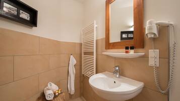 A bathroom with a white sink, a mirror, a towel rack, and a hairdryer on the wall.