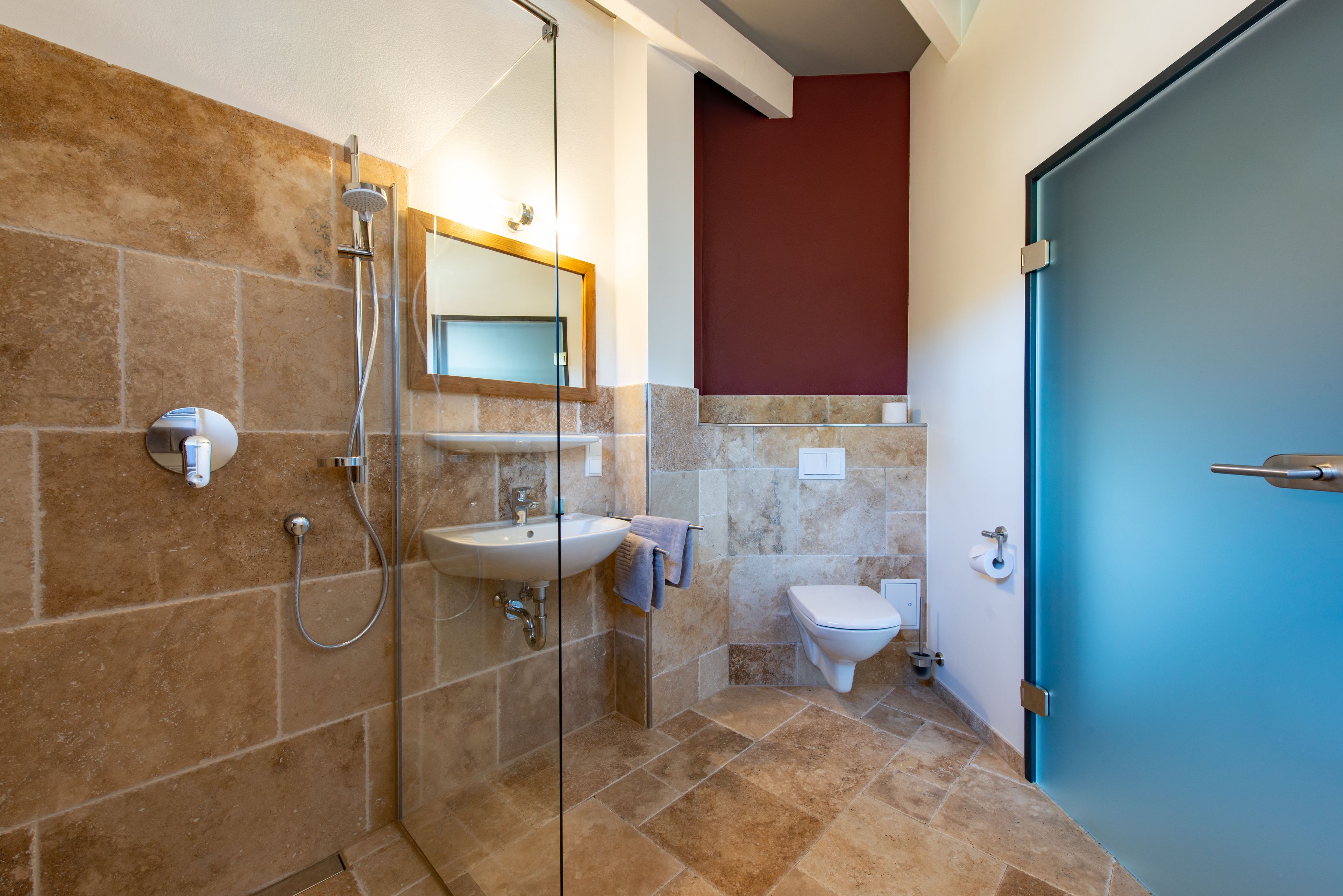 A bathroom with a glass-enclosed shower, a sink, and a toilet.