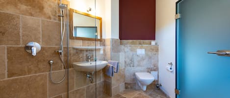 A bathroom with a glass-enclosed shower, a sink, and a toilet.