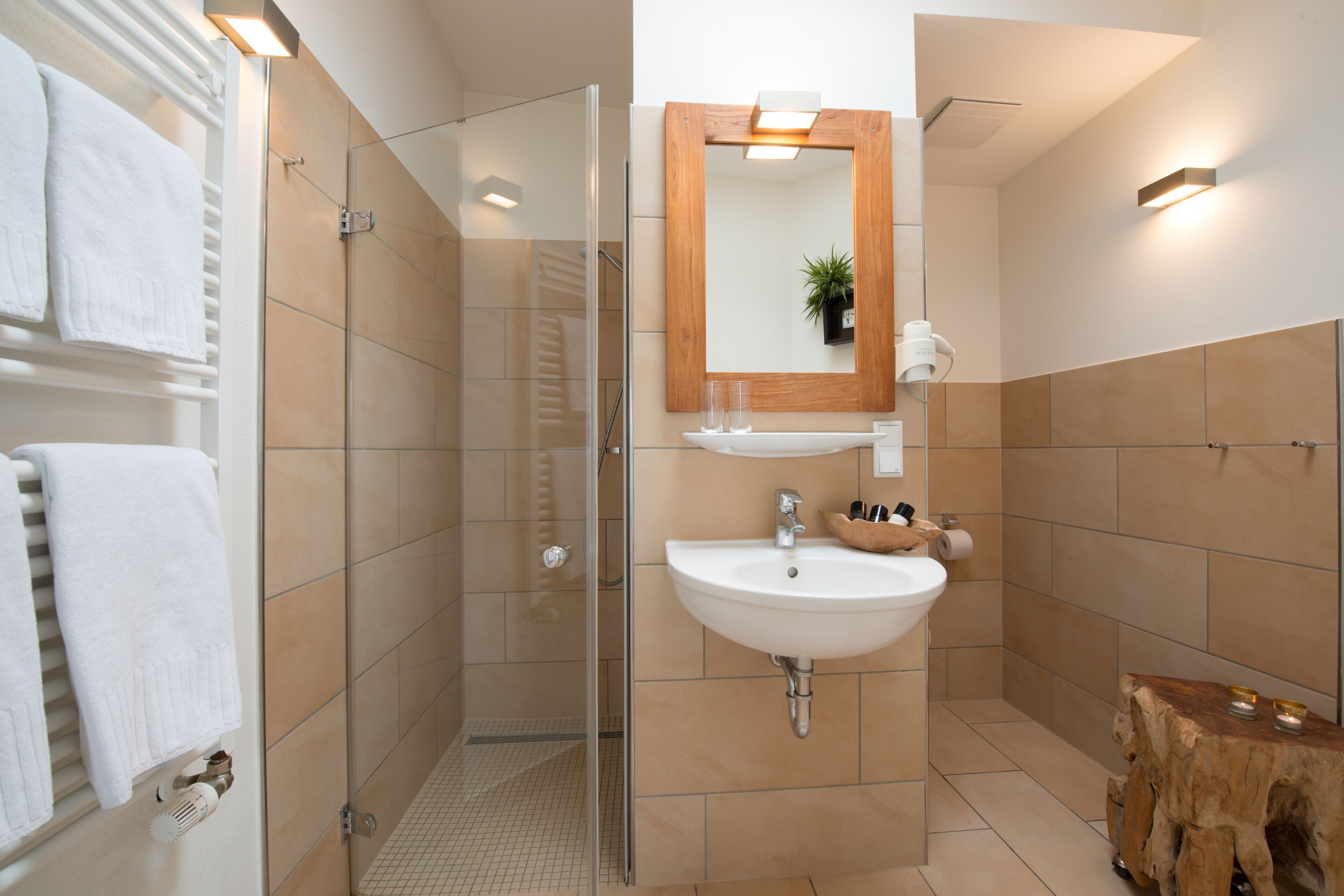 A modern bathroom with a glass-enclosed shower, a white sink, and a wooden vanity.