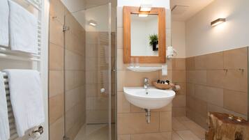 A modern bathroom with a glass-enclosed shower, a white sink, and a wooden vanity.