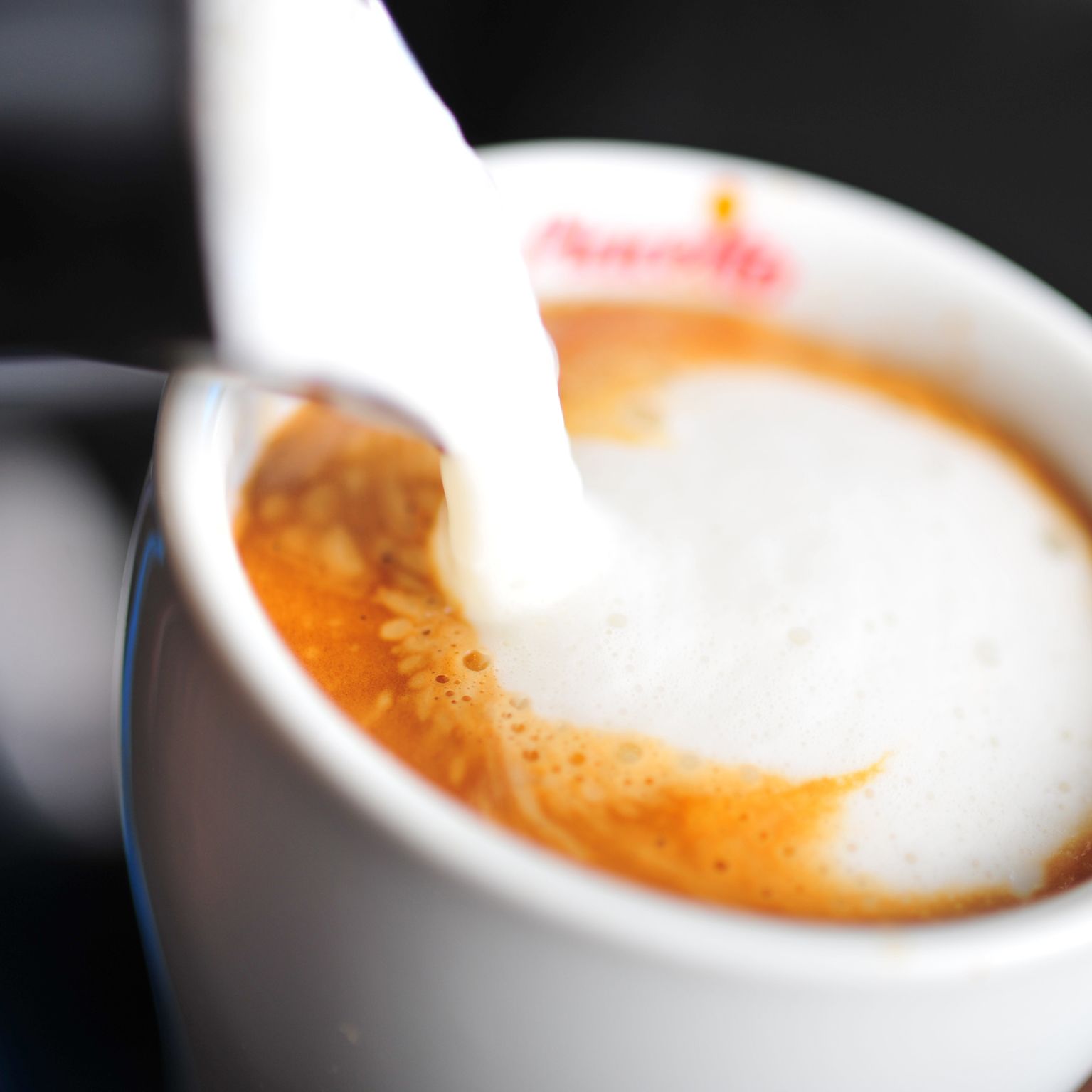 Un primo piano di una tazza di caffè con un cucchiaino.