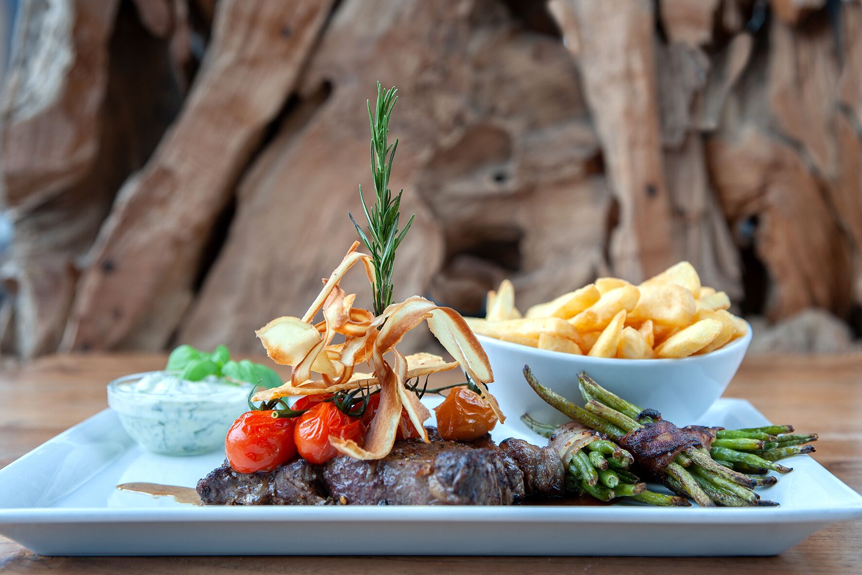 A plate of food with steak, asparagus, cherry tomatoes, and a side of fries.
