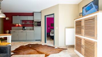 A modern kitchen with grey cabinets, a wooden cabinet with a TV, and a cowhide rug.