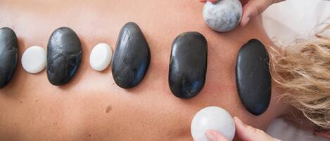 Masaje con piedras colocadas sobre la espalda de una persona.