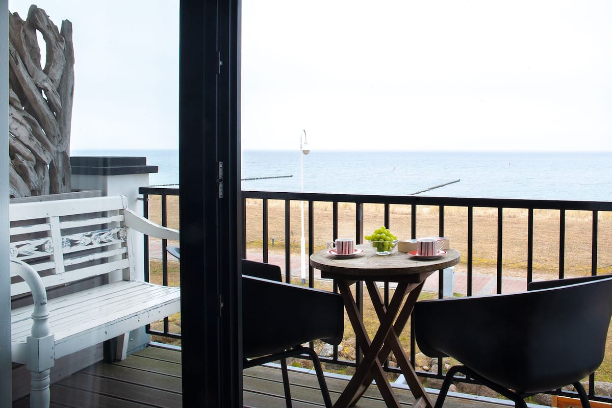 Un balcon avec une table et des chaises, donnant sur une plage.