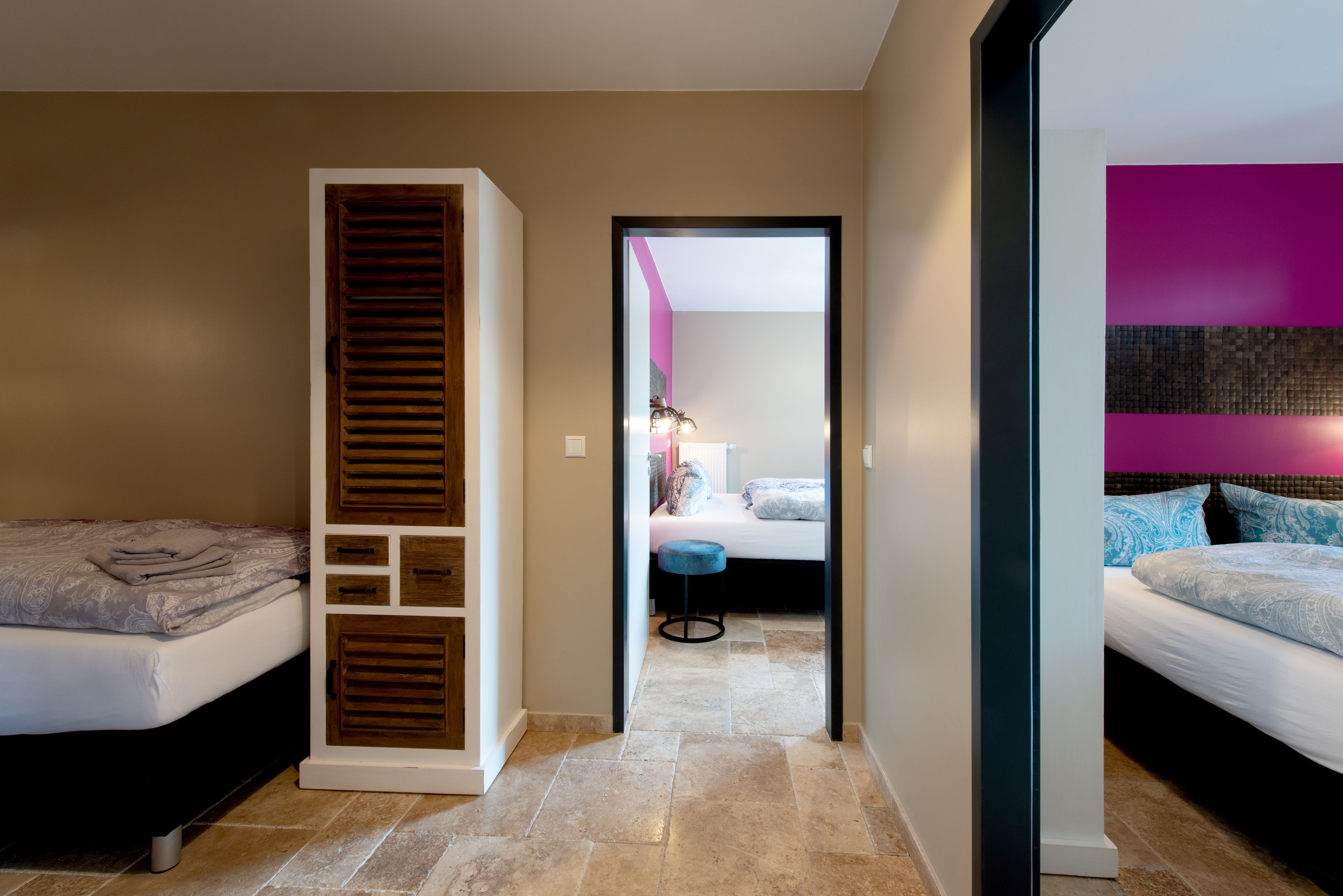 Quarto com cama, guarda-roupa e banheiro visível através de uma porta aberta.