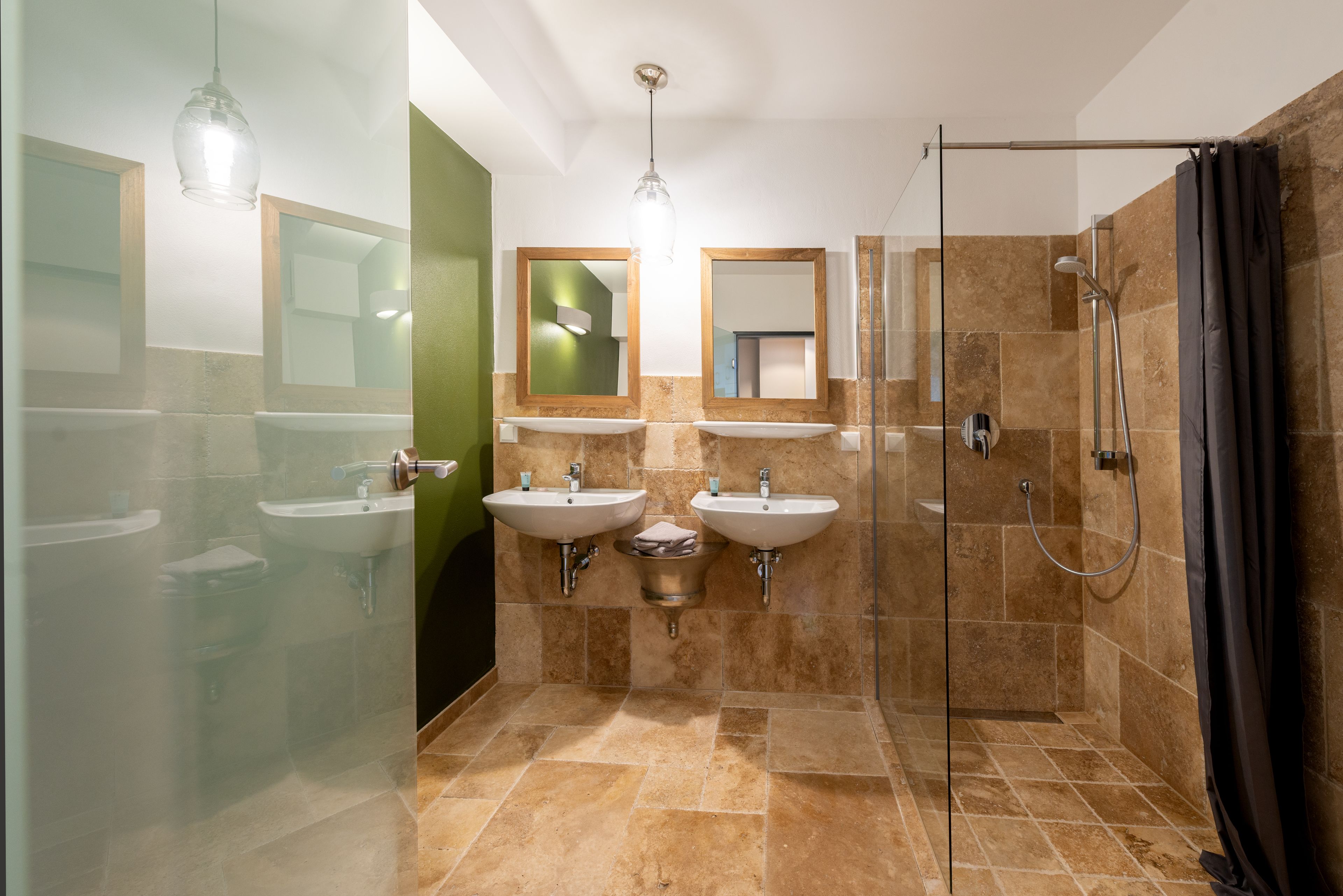Une salle de bain moderne avec deux lavabos, une douche et un espace douche fermé par des parois de verre.