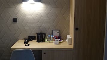 A compact room with a wooden desk, a chair, a wall-mounted light, and a door.