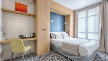 Une chambre d’hôtel avec un lit, un bureau, une chaise et une grande fenêtre.