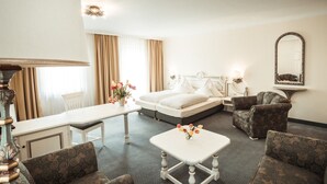 Ein Hotelzimmer mit einem Bett, zwei Sesseln, einem Tisch, einer Lampe und einem Spiegel.