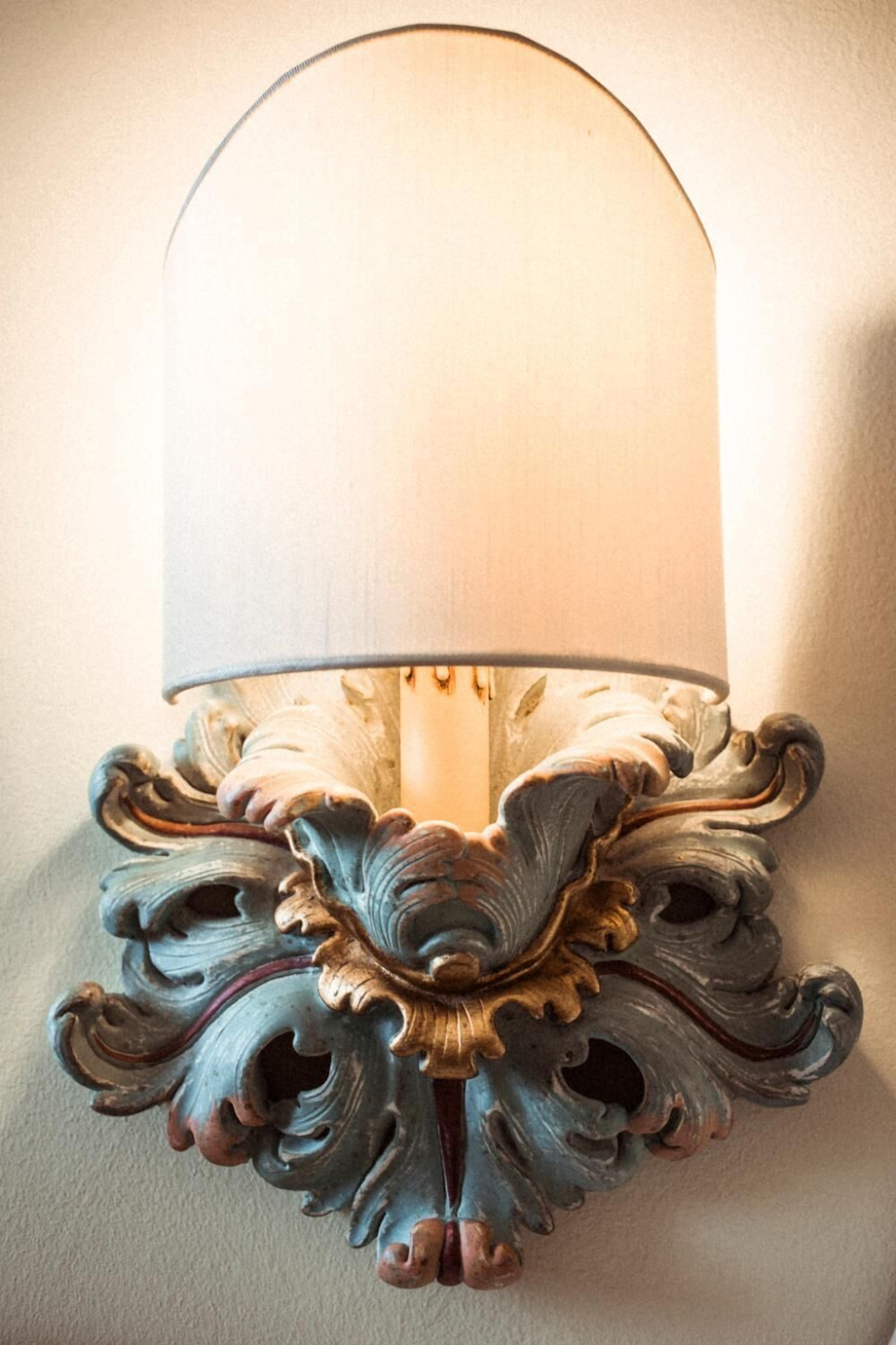 A wall-mounted lamp with a decorative base and a lighted shade.